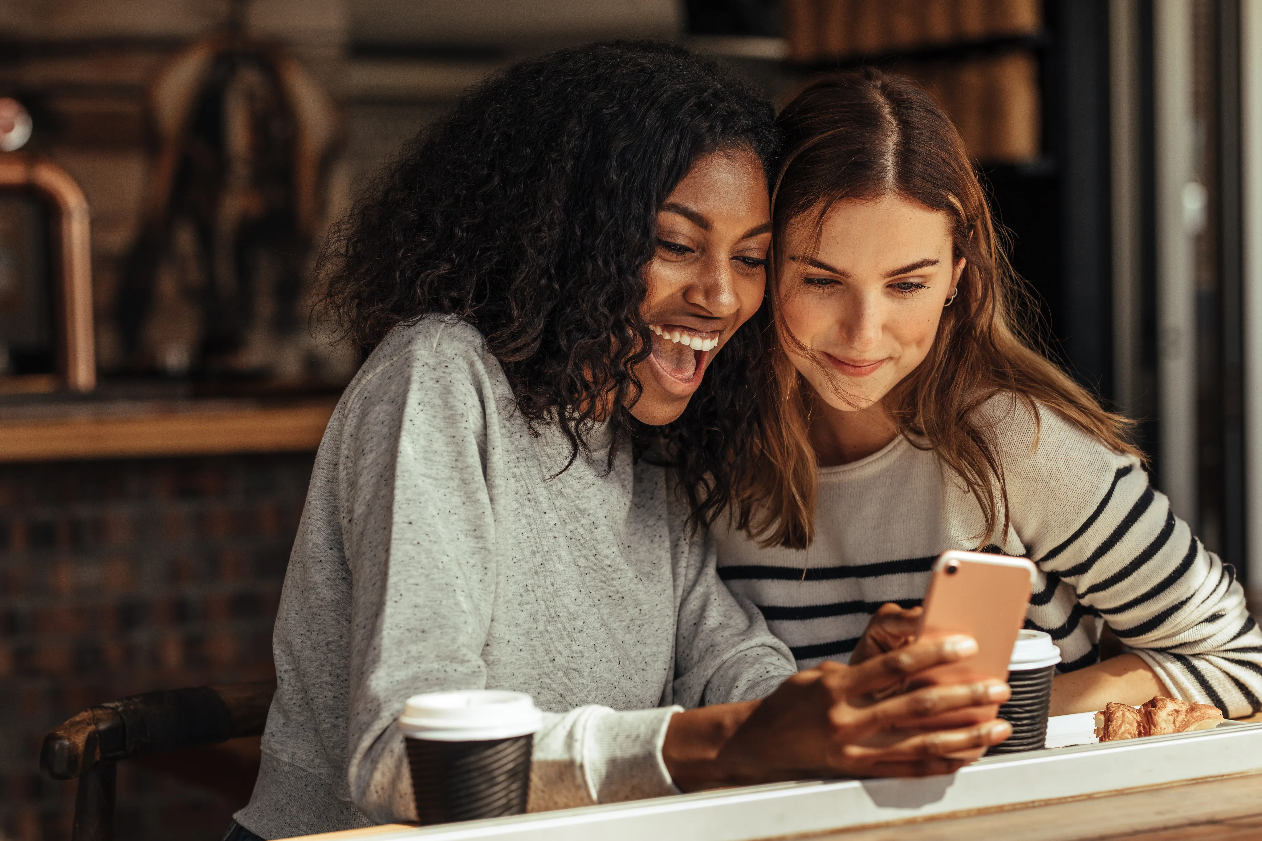 Two friends smiling and looking at a phone together